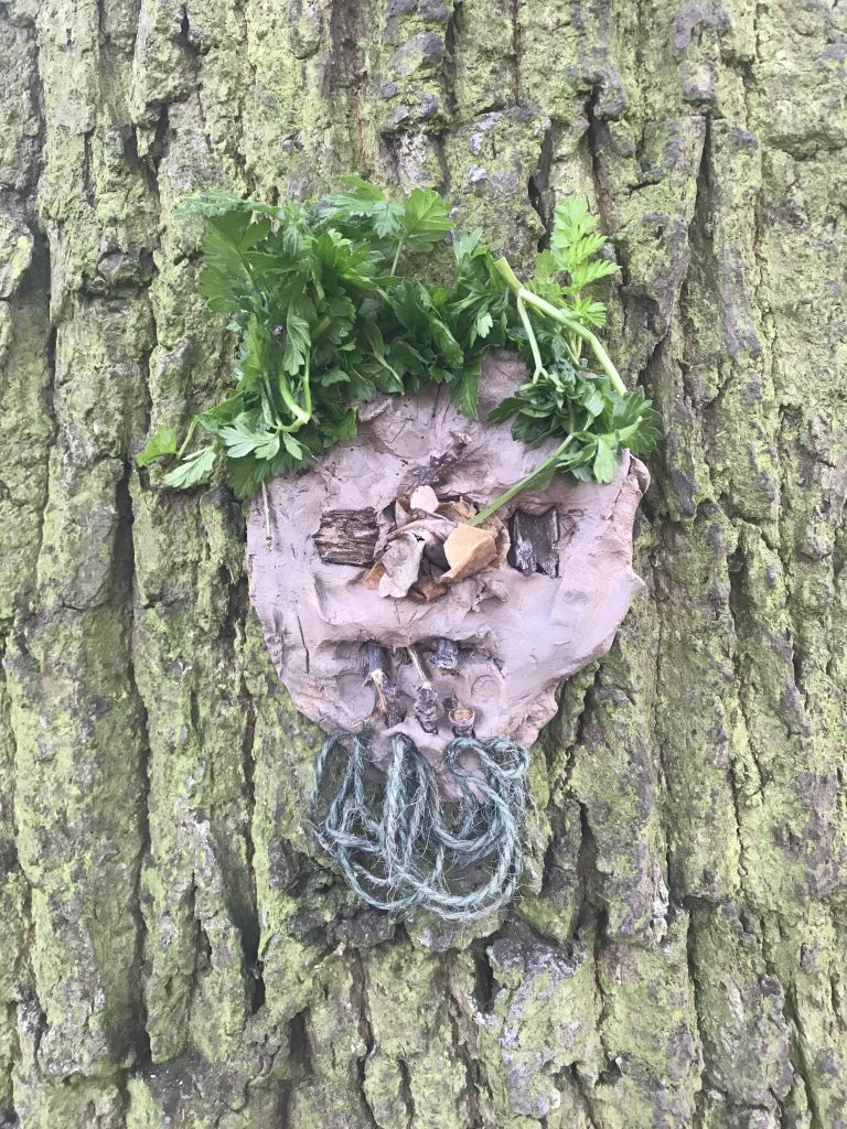 Monster made from clay and natural materials on the bark of a tree.